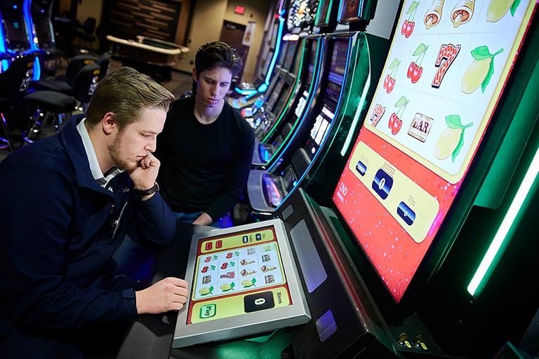 Two students sitting in front of a slot machine