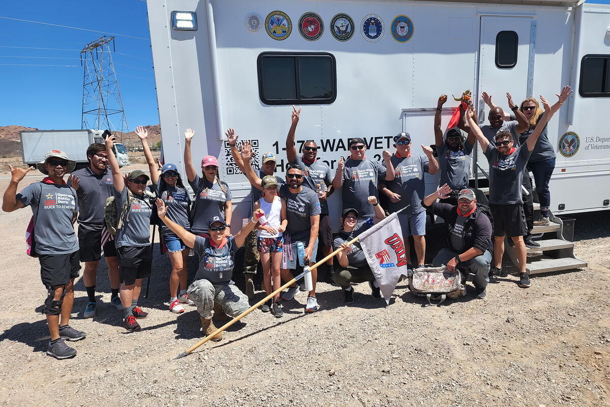Group of people, smiling and raising their arms in front of a Vet Center van