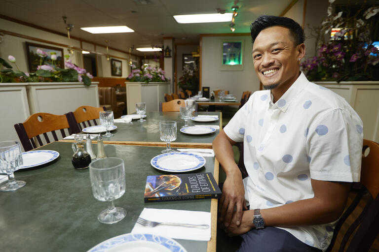 A man sits smiling at a restaurant table.