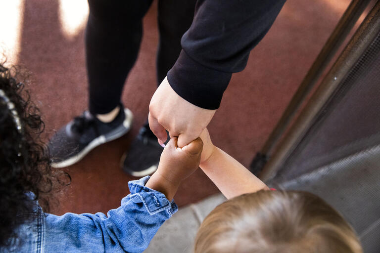 close up of two children holding the hands of an adult